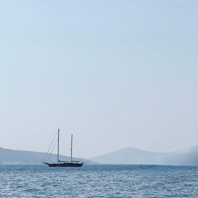 Sailboat on a calm sea with a hazy mountain range in the background